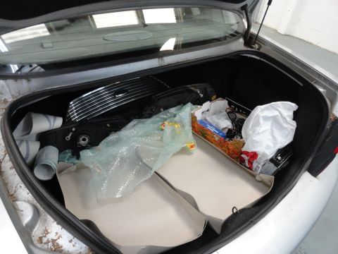 1999 Ford Fairlane - The trunk of a car is filled with various parts and storage containers, suggesting it is being used for storage.