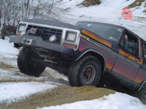 1993 Ford Bronco - Ford Bronco navigates a snowy, off-road trail with a winch and custom bumper.