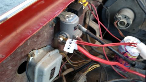 1981 Ford Bronco - A close-up view of the engine bay of a red vehicle, showing electrical components including a starter solenoid, wiring, and a relay. A whit…