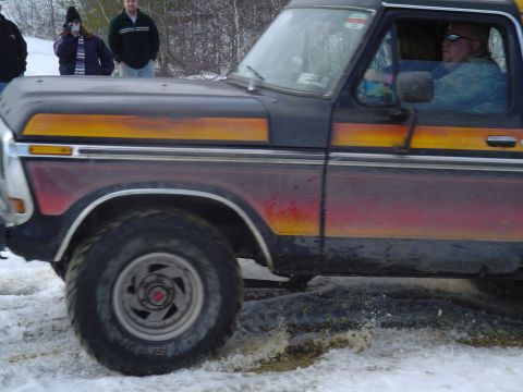 1993 Ford Bronco - This vintage Ford pickup truck navigates a snowy and muddy terrain with a driver behind the wheel.