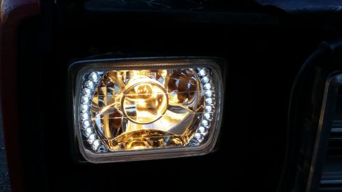 1981 Ford Bronco - A close-up of a modified headlight assembly on a vehicle, featuring a clear lens with a halo of white LED accent lights surrounding the mai…