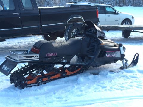 2000 Ford E350 - A black Yamaha snowmobile sits in the snow next to a black pickup truck and a white SUV with a trailer. The snowmobile has a VMAX-4 decal o…