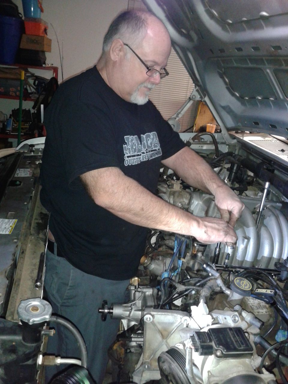 Man working on an open vehicle engine.