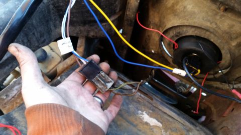 1981 Ford Bronco - A close-up view of a person's hand holding a wiring harness connector with multiple colored wires attached. The connector appears to be par…