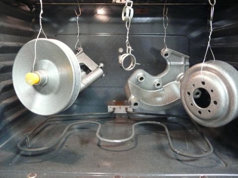 Automotive parts hanging in an oven, ready for curing.