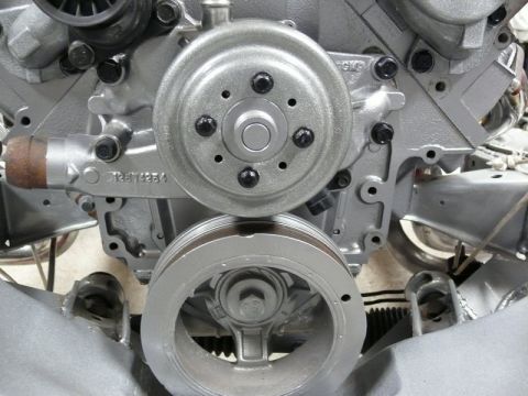 Silver engine block with water pump and crankshaft pulley, showing part number.