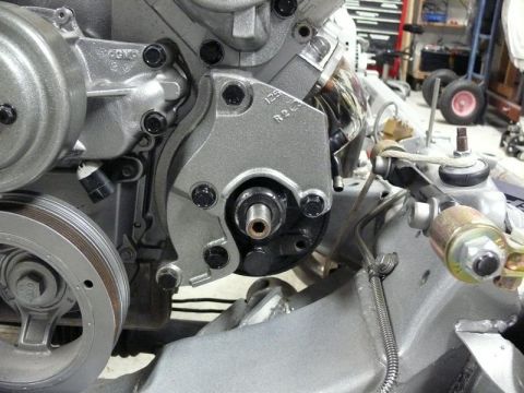Silver engine component with pulleys and bolts attached to vehicle chassis