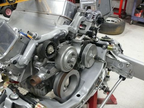 Close-up of a silver engine assembly with pulleys, belts, and alternator.