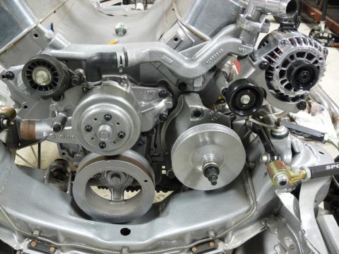 Silver engine assembly with alternator, water pump, and pulleys.