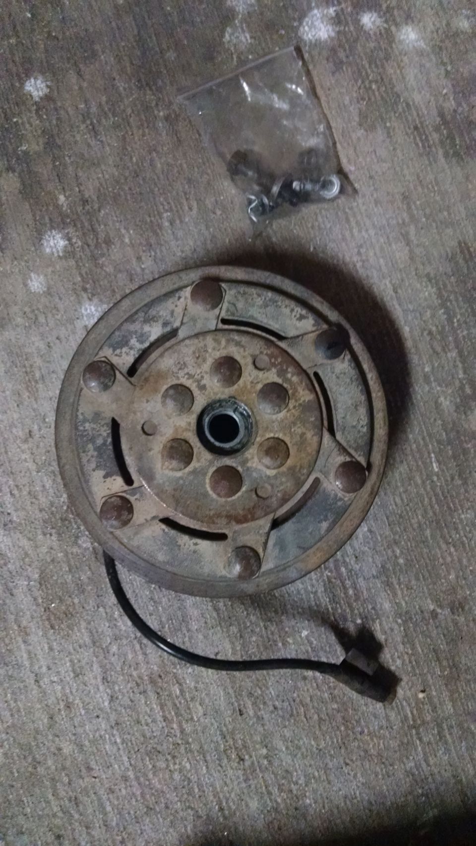 Rusty clutch assembly with wire and connector on concrete.