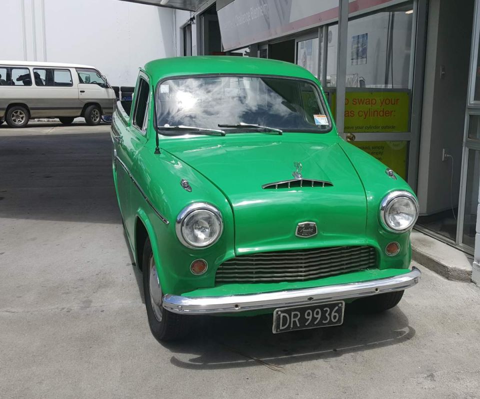 Front view of a vintage green pickup truck with a chrome grille and license plate DR 9936.
