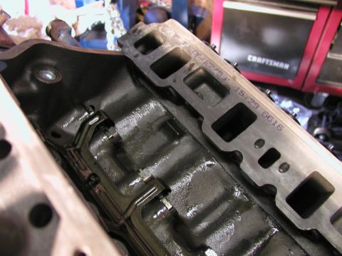 1988 Ford Bronco - Engine parts, including a cylinder head and intake manifold, are shown in a workshop setting.