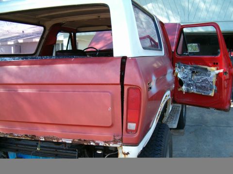 1979 Ford Bronco - Rear view of a red and white 1979 Ford Bronco with the driver's door open.