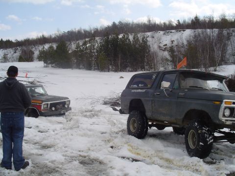 1993 Ford Bronco - Two SUVs stuck in the snow, one is being towed by the other.