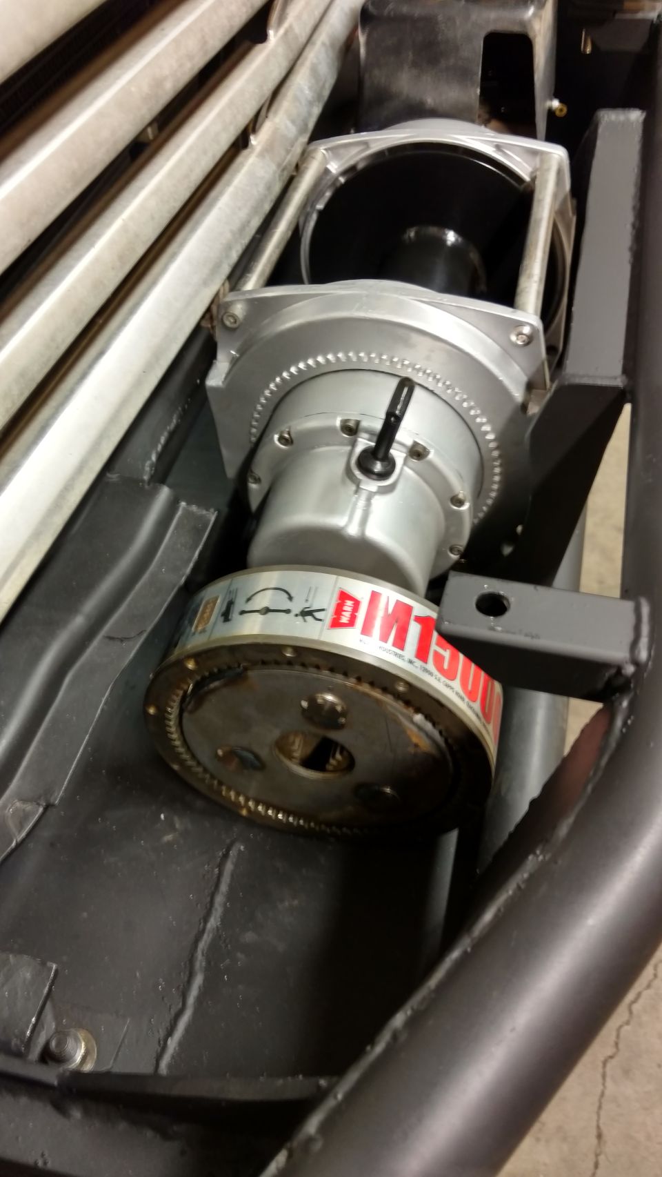 Close-up of a WARN M1500 winch motor with a silver housing and geared drum.