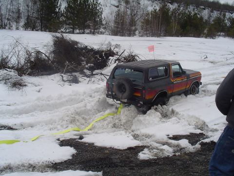 1993 Ford Bronco - A Ford Bronco is stuck in deep snow, with a tow strap attached to its rear bumper.