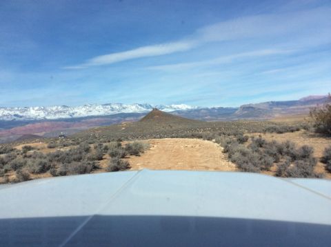 1979 Ford Bronco - The front hood of a light-colored vehicle is visible in the foreground, looking out over a desert landscape with a prominent conical hill a…