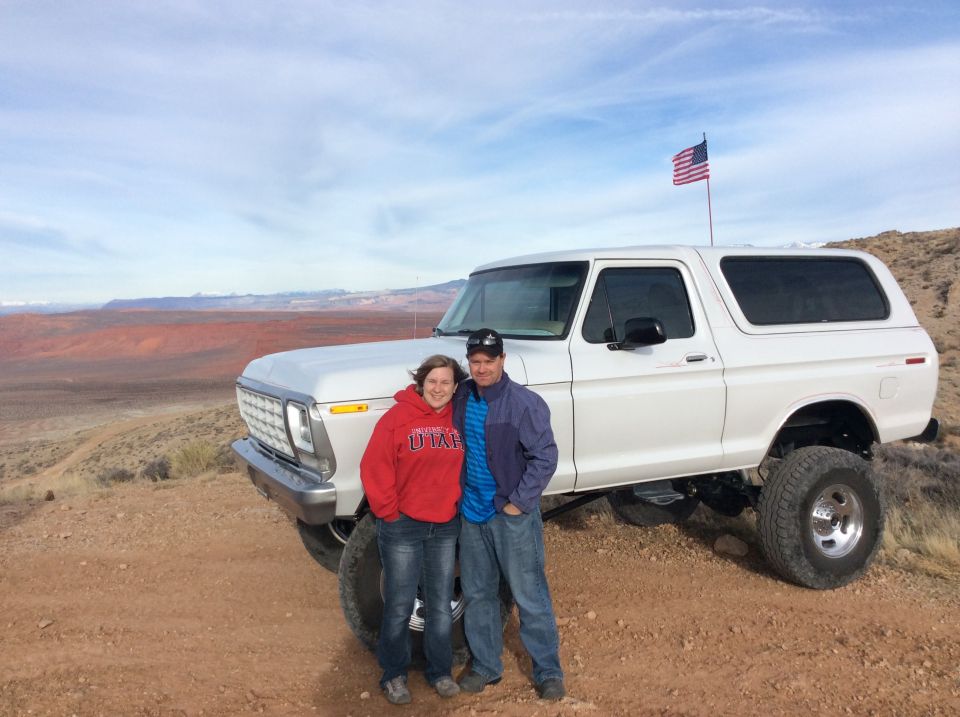 Couple in front of a white 1979 Ford Bronco with an American flag.