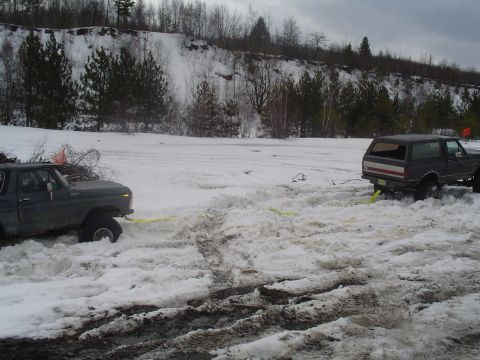 1993 Ford Bronco - Two Ford Broncos are stuck in a snowy landscape, one being towed by the other.