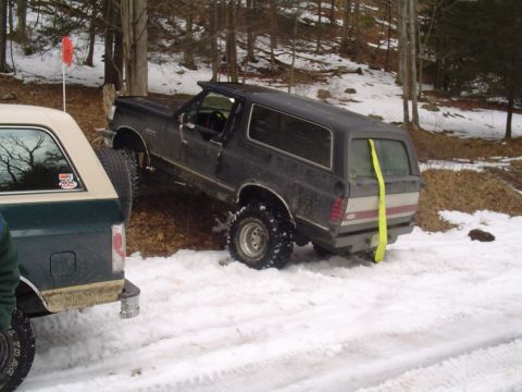 1993 Ford Bronco - Two Ford Broncos in a snowy wooded area, one appears stuck.