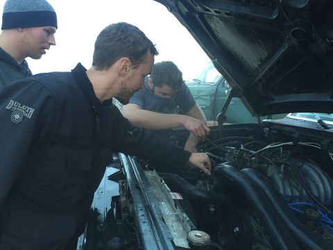 1989 Ford Bronco - Working on the engine of a 1989 Ford Bronco with friends. Another vehicle is parked behind.