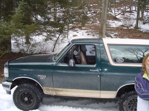 1993 Ford Bronco - A green and tan Ford Bronco is parked in the snow, with trees in the background.