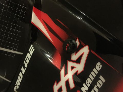 2014 Dodge 1500 - Close-up of a black vehicle panel displaying 'PRO-LINE' and flame graphics, with a 'TL' branded fastener.