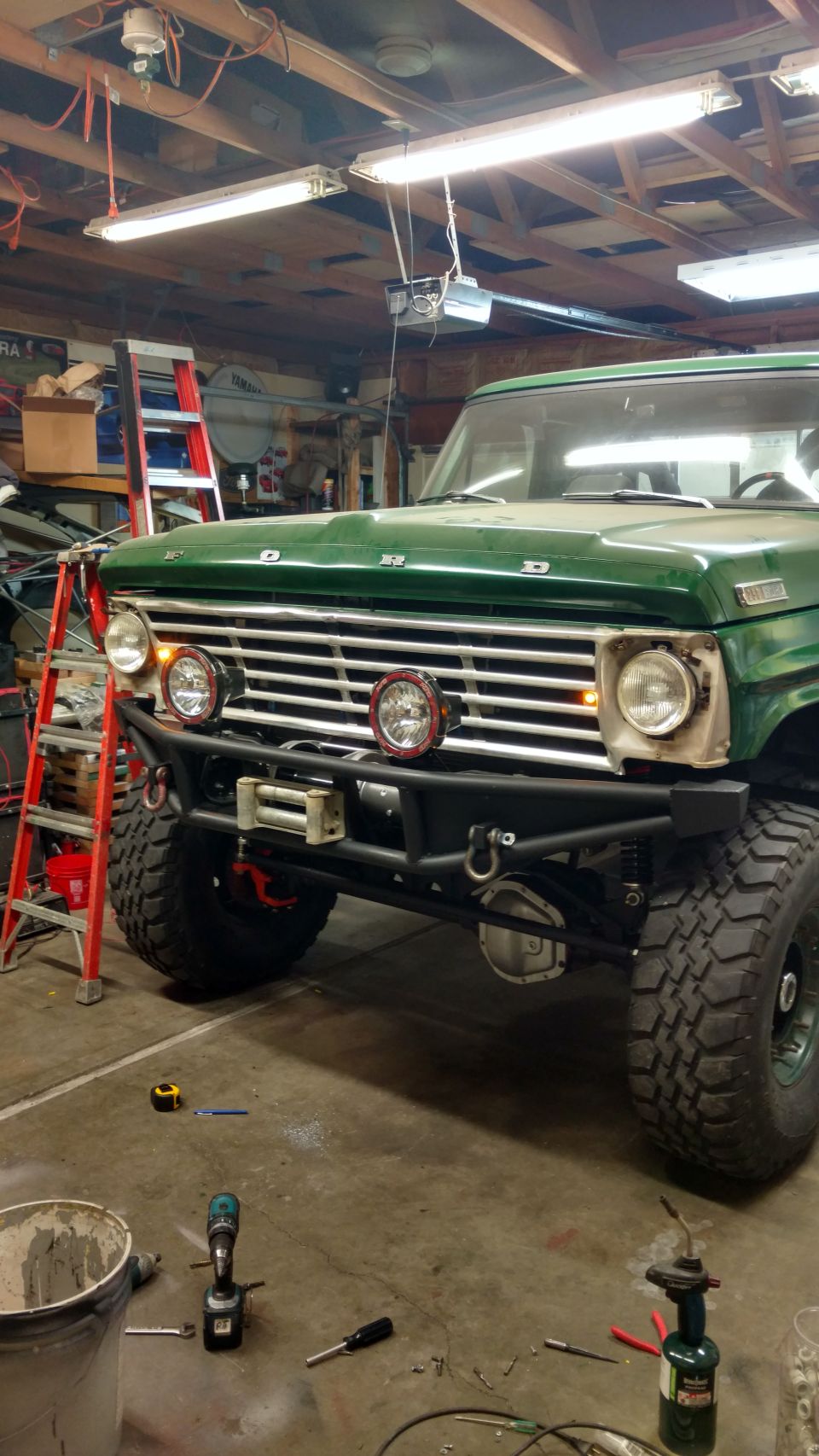 Green 1967 Ford F-250 with custom bumper and winch in a garage