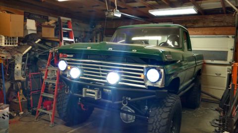 1967 Ford F-250 - A modified green Ford pickup truck sits in a cluttered garage, ready for off-road adventures.