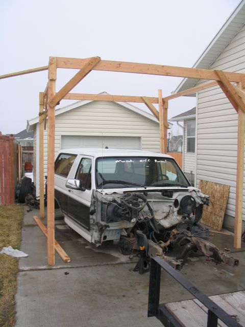 1996 Ford Bronco - 1996 Ford Bronco undergoing disassembly in a driveway, supported by jack stands.