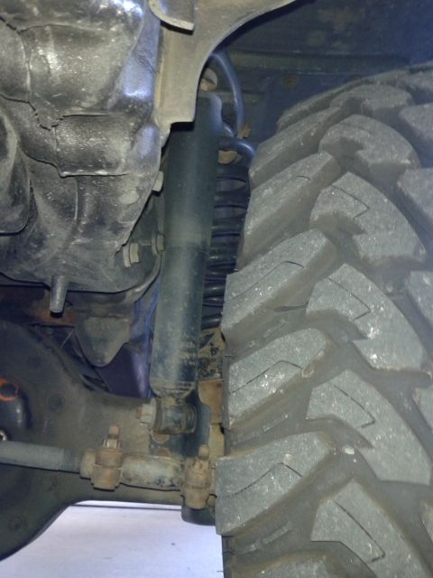 1996 Ford Bronco - Detail shot of a vehicle's tire and suspension system, showing off-road tread.