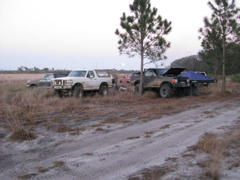 1994 Ford Bronco - Several trucks, including a white Ford Bronco, are parked in a field with a tent set up.