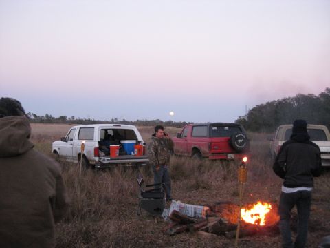 1994 Ford Bronco - People gathered around a campfire with several Ford Broncos in a field during twilight.