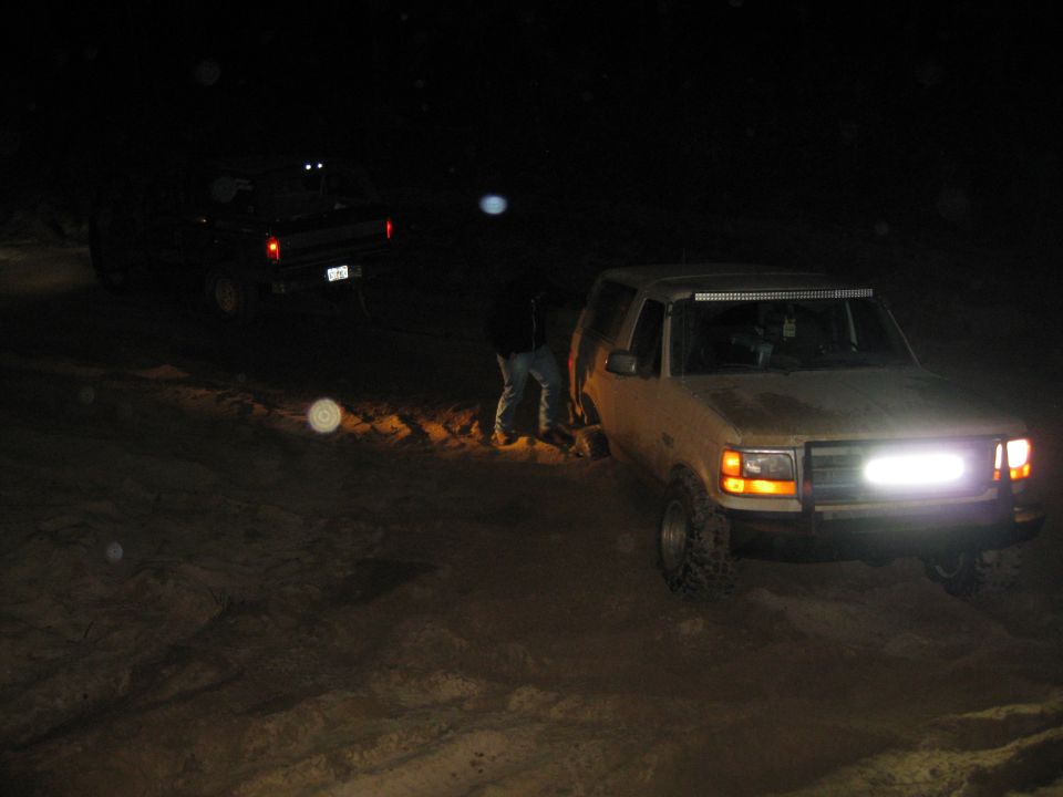 1992 Ford Bronco with light bar and front light, and another truck behind it at night