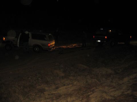 1994 Ford Bronco - Two vehicles are visible at night, one with its door open.