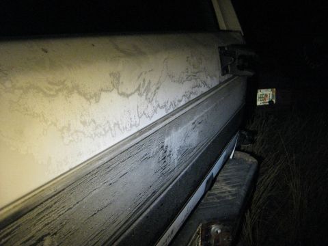 1994 Ford Bronco - The rear quarter panel of a vehicle shows dirt and grime, with a license plate visible in the dark background.