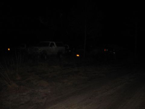 1994 Ford Bronco - A white SUV is parked in a dark, grassy area at night, with another vehicle's lights visible in the background.