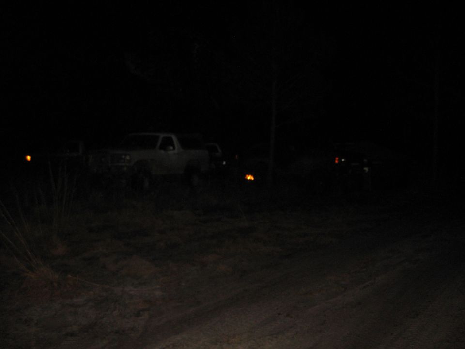 White SUV parked at night with another vehicle visible in the distance