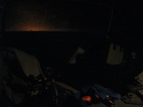 1994 Ford Bronco - The interior of a vehicle is dimly lit, with the steering wheel and dashboard visible. Items are scattered in the back seat.