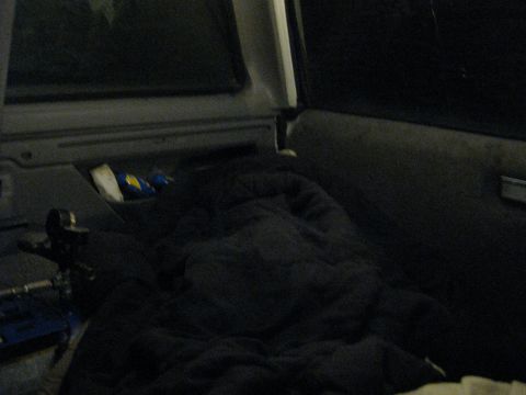 1994 Ford Bronco - The interior of a vehicle is covered in a dark blanket, with a blue tool bag visible on the floor.