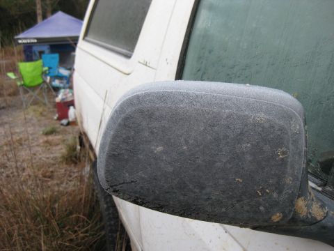 1994 Ford Bronco - Side mirror of a white vehicle is covered in frost, with camping chairs and a tent visible in the background.