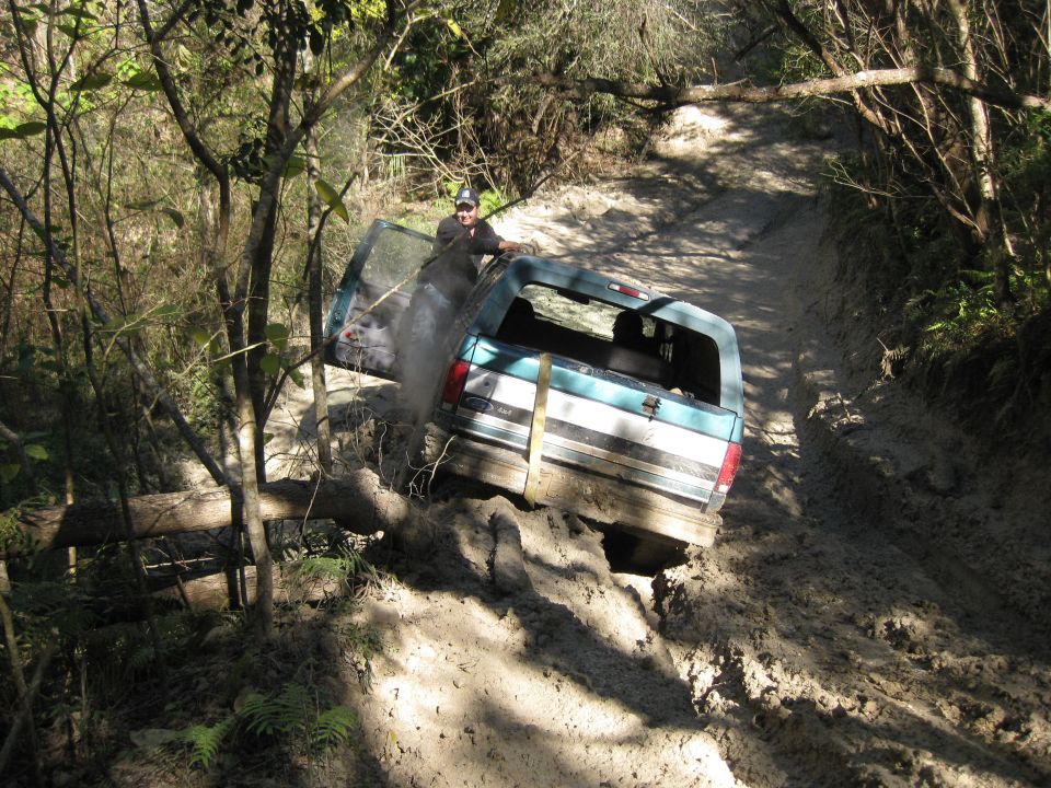 Ford Bronco stuck in mud on a trail, driver's door open