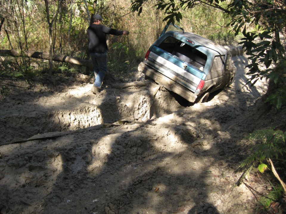 Teal and white 1994 Ford Bronco stuck in mud, rear view