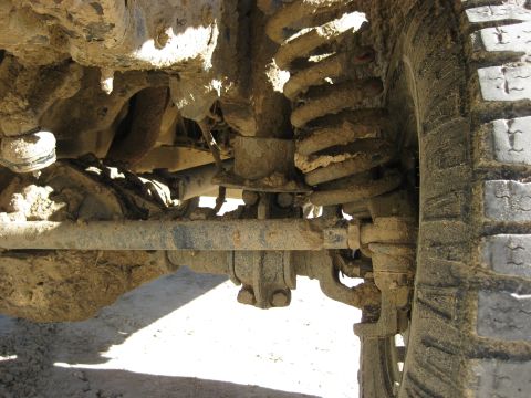 1994 Ford Bronco - Muddy suspension components and tire tread are visible in this close-up shot.
