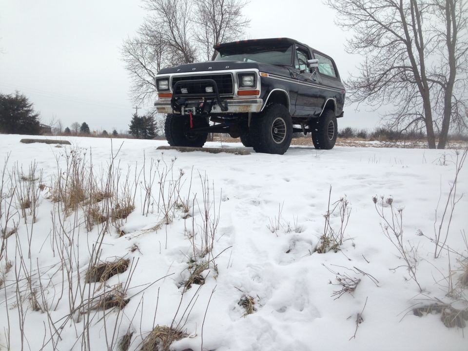 Black Ford Bronco with a winch on the front bumper, parked in the snow