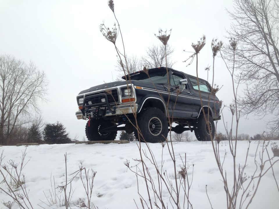 Black 1978 Ford Bronco with a brush guard and winch parked in snow