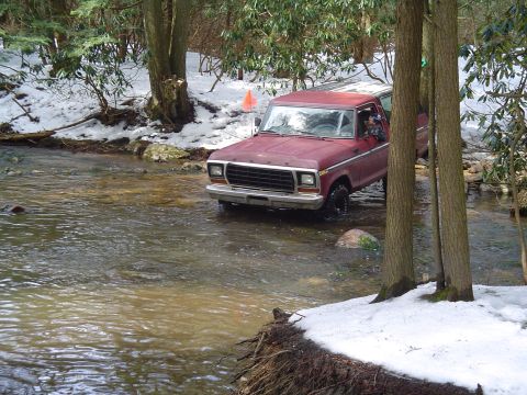1993 Ford Bronco - A red 1978 Ford Bronco navigates a stream in a snowy, wooded environment.