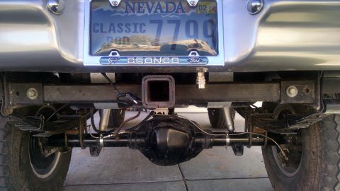 1979 Ford Bronco - The rear underside of a Ford Bronco, its axle, leaf springs, and a trailer hitch assembly.