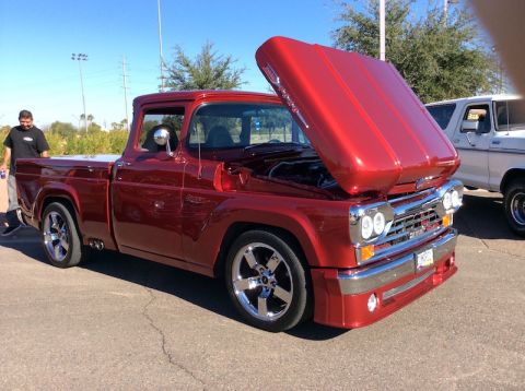 1979 Ford Bronco - A custom red pickup truck is parked outside with its hood open, next to another vehicle.
