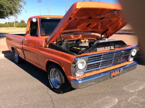 1979 Ford Bronco - This orange 1967 Ford F-100 pickup truck is shown with its hood open, revealing the engine bay.
